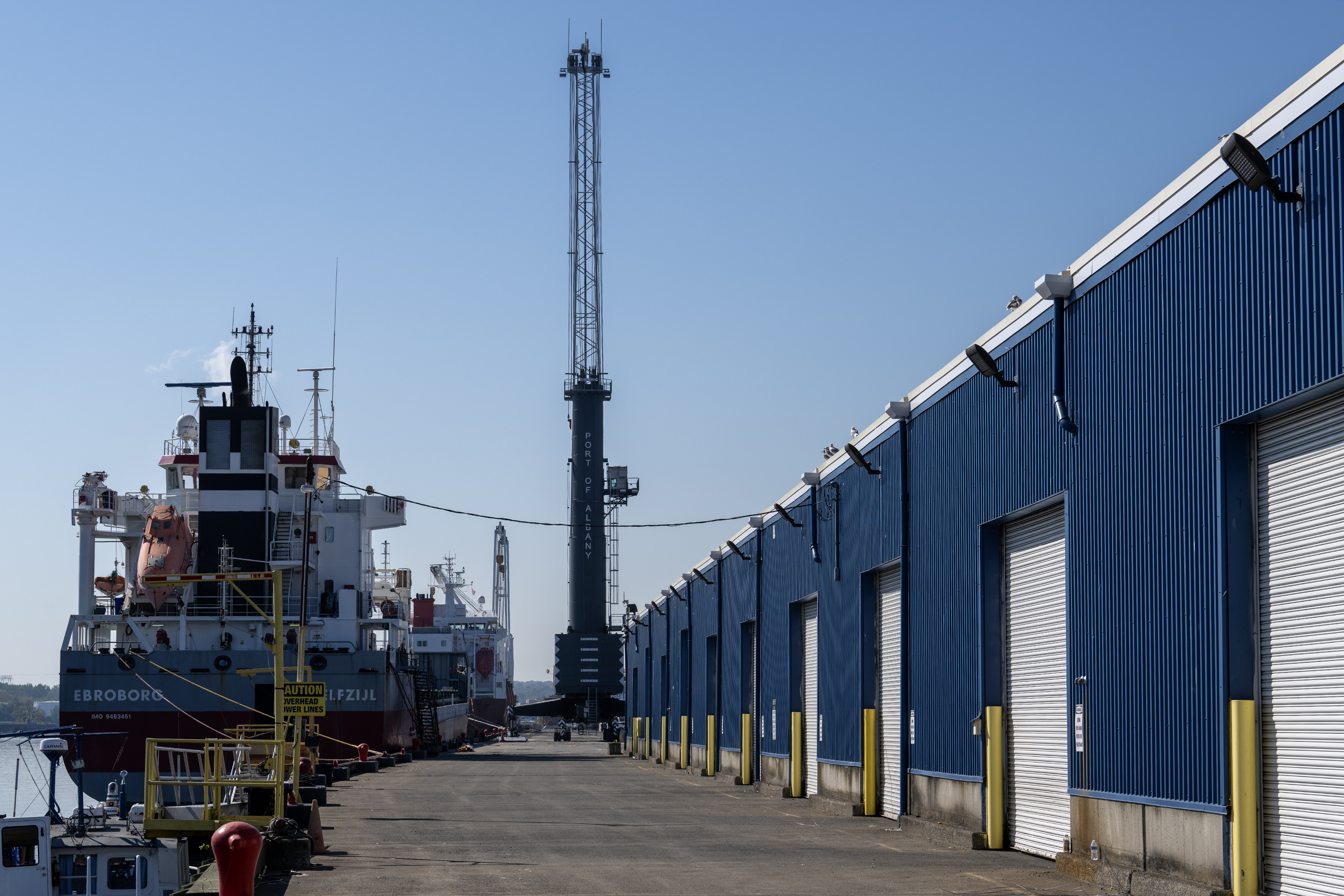 Sheds along wharf with crane and ship in background