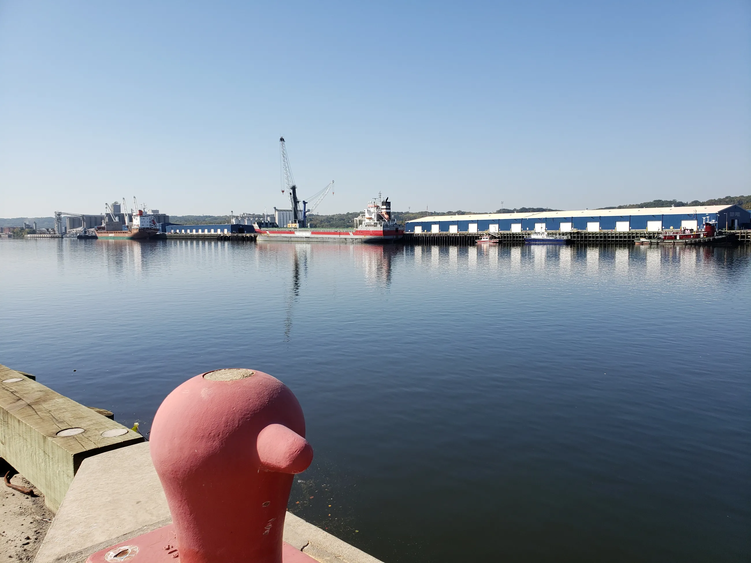View of Port of Albany warehouses and ships at dock with red bollard in the forefront